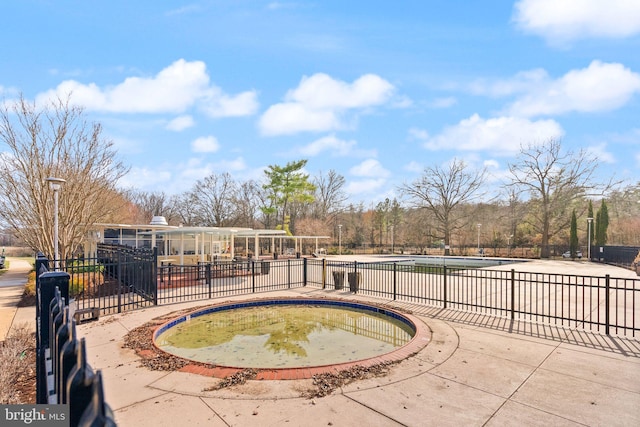 view of swimming pool featuring a hot tub and fence