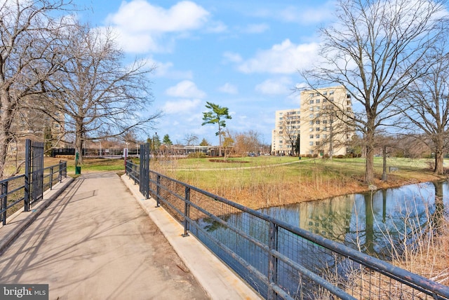 surrounding community with a water view and fence