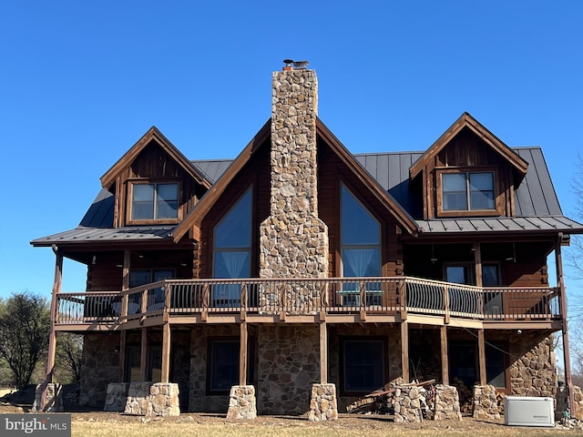 back of property with stone siding, a chimney, a standing seam roof, and metal roof