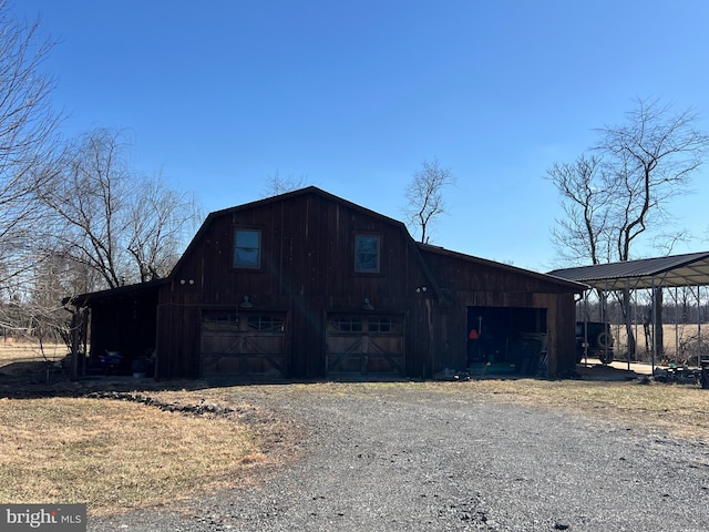 view of side of home featuring a barn, a detached garage, a gambrel roof, an outbuilding, and driveway