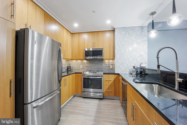 kitchen with dark stone counters, a sink, ornamental molding, stainless steel appliances, and backsplash