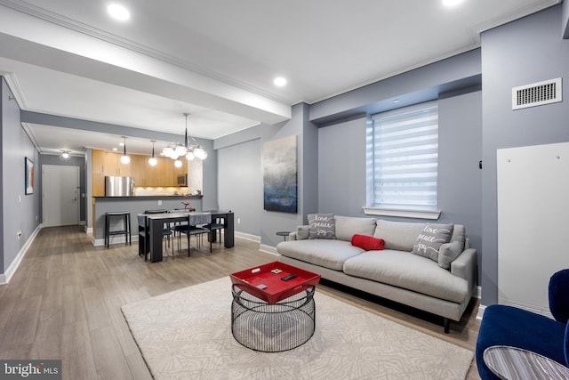 living room featuring visible vents, baseboards, light wood-style floors, and ornamental molding