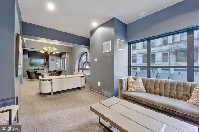 carpeted living room with visible vents, baseboards, and a notable chandelier