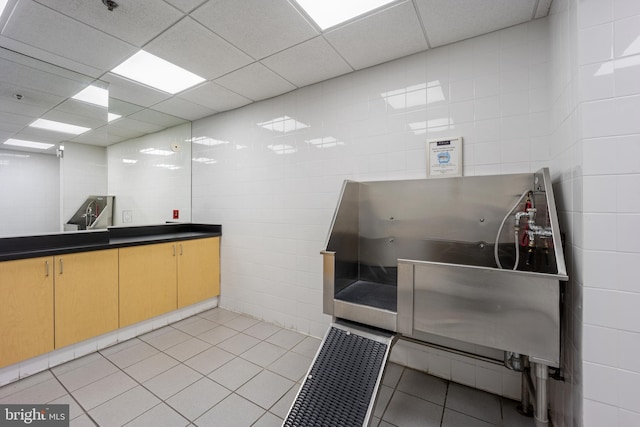 miscellaneous room featuring tile walls, light tile patterned floors, and a drop ceiling