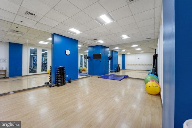 gym featuring wood finished floors, visible vents, and a drop ceiling