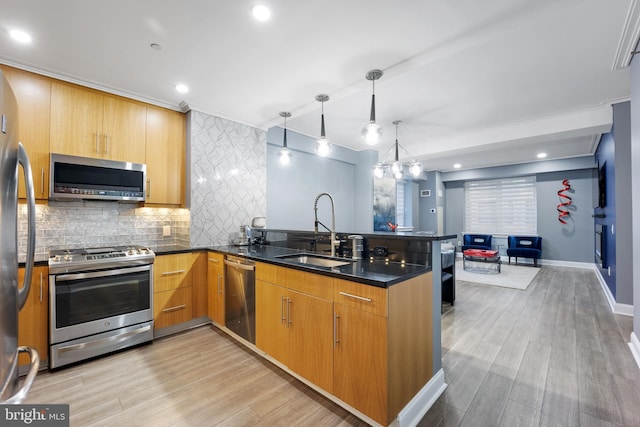 kitchen featuring a sink, stainless steel appliances, light wood-type flooring, and a peninsula