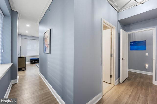 corridor with baseboards, light wood-style floors, and ornamental molding