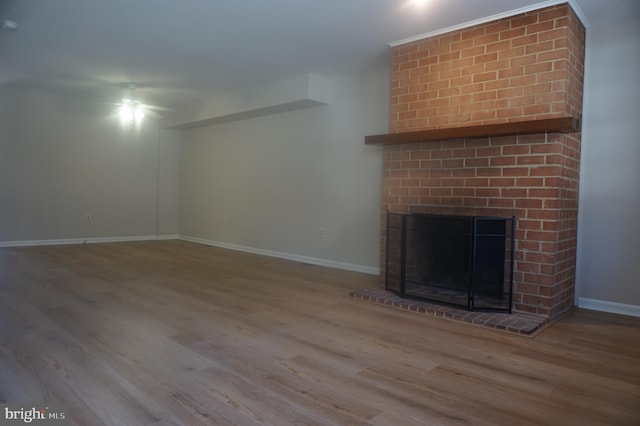 unfurnished living room featuring a fireplace, baseboards, and wood finished floors