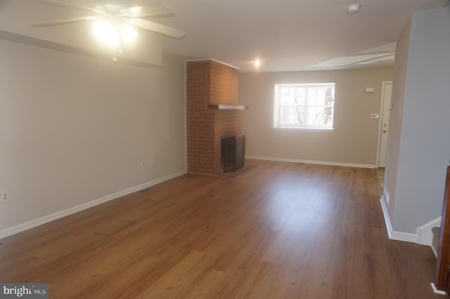 unfurnished living room with light wood-type flooring, baseboards, a brick fireplace, and ceiling fan