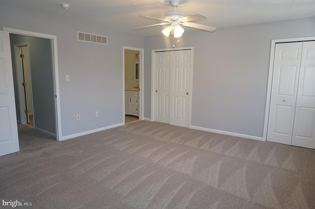 unfurnished bedroom featuring visible vents, multiple closets, connected bathroom, carpet, and baseboards