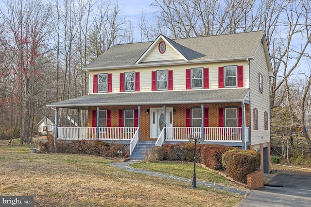 view of front of property with driveway, roof with shingles, covered porch, a front lawn, and a garage