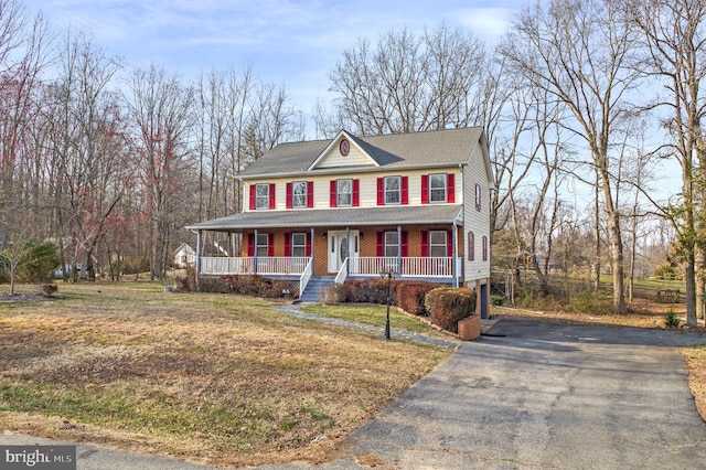 view of front of house with aphalt driveway, a porch, and a front lawn