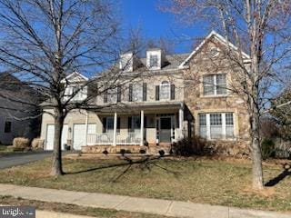 view of front of property featuring a porch, an attached garage, driveway, and a front yard