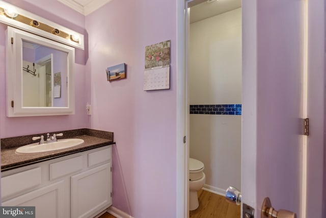 bathroom with toilet, wood finished floors, and vanity