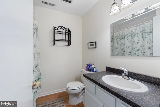 bathroom with visible vents, toilet, a shower with curtain, wood finished floors, and vanity