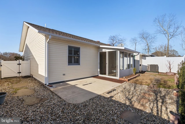 back of property featuring a gate, a patio, fence, a sunroom, and central AC unit