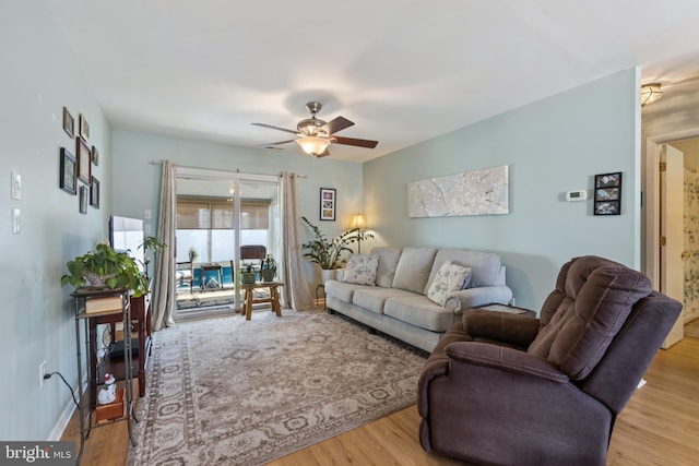 living room with ceiling fan, baseboards, and wood finished floors