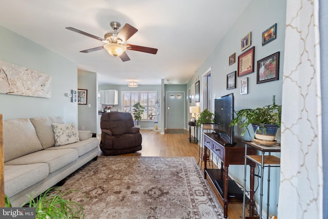 living room featuring baseboards, ceiling fan, and wood finished floors