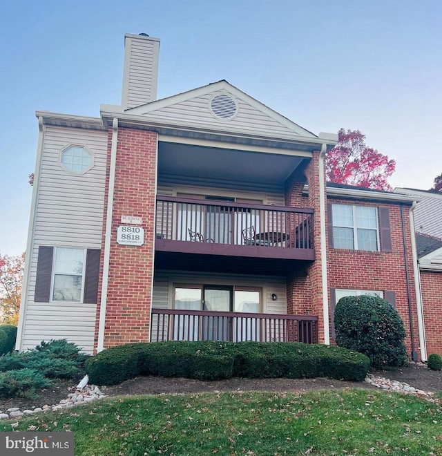 exterior space featuring a balcony, brick siding, and a chimney