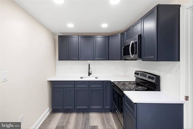 kitchen with tasteful backsplash, appliances with stainless steel finishes, light wood-type flooring, and a sink