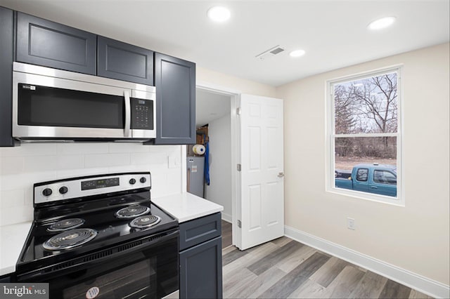 kitchen with visible vents, light wood-style flooring, appliances with stainless steel finishes, light countertops, and decorative backsplash