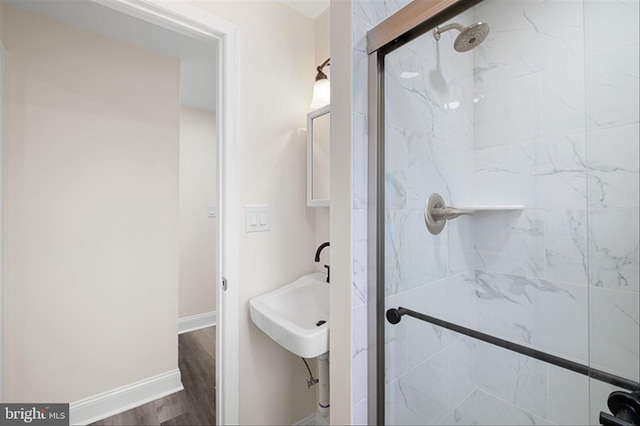 bathroom with wood finished floors, baseboards, and a stall shower