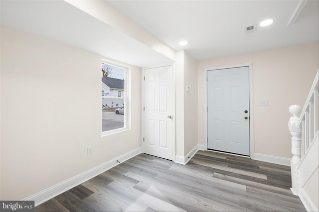 foyer with wood finished floors, visible vents, baseboards, recessed lighting, and stairs