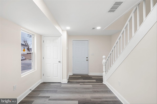 entrance foyer with visible vents, stairway, baseboards, and wood finished floors