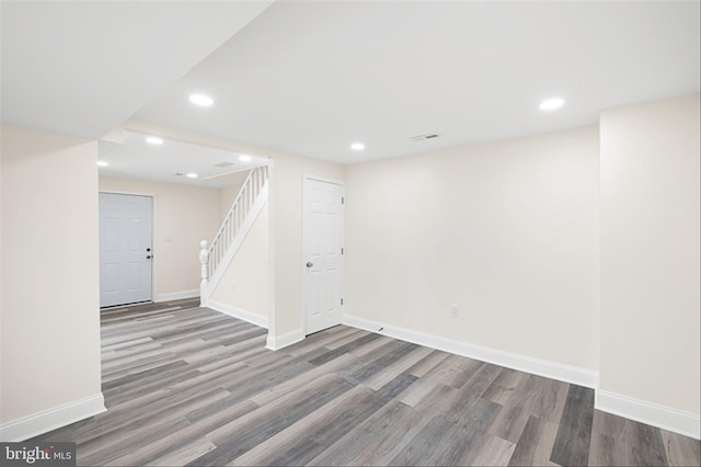 basement with recessed lighting, stairway, baseboards, and wood finished floors