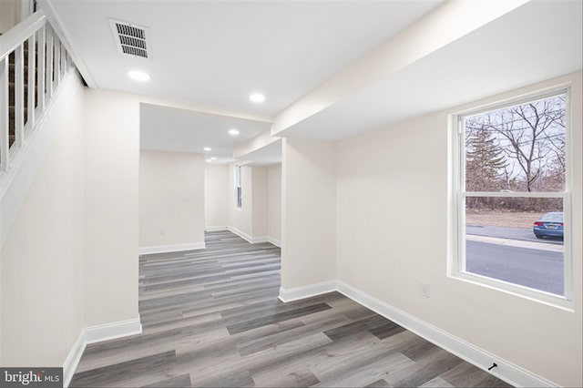 below grade area featuring visible vents, baseboards, wood finished floors, and stairs