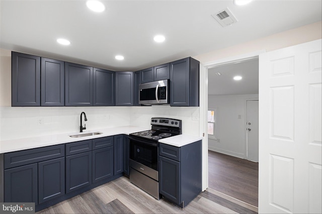 kitchen with visible vents, light countertops, appliances with stainless steel finishes, light wood-style floors, and a sink