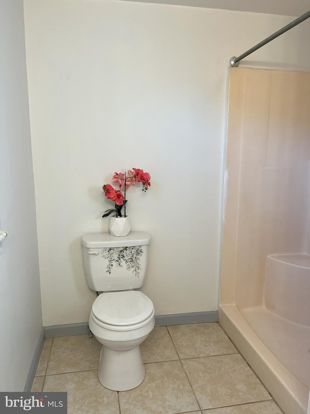 bathroom with tile patterned floors, toilet, and a stall shower