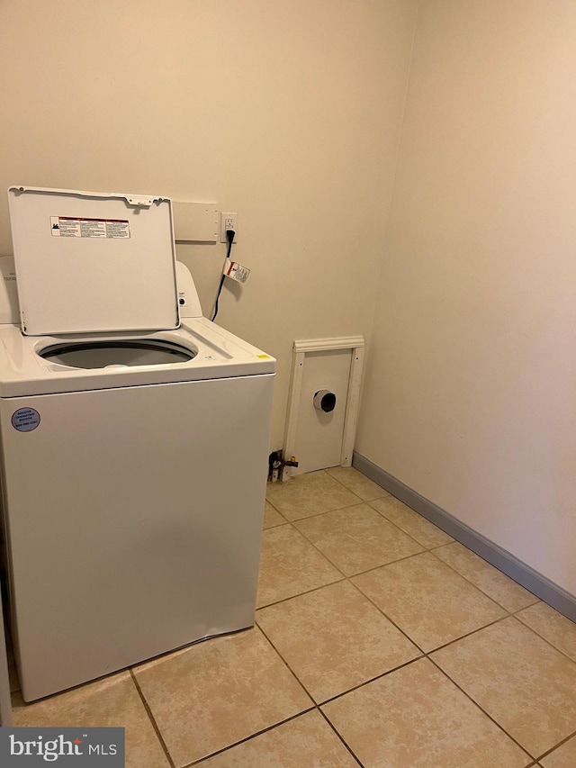 clothes washing area featuring light tile patterned floors, baseboards, washer / clothes dryer, and laundry area