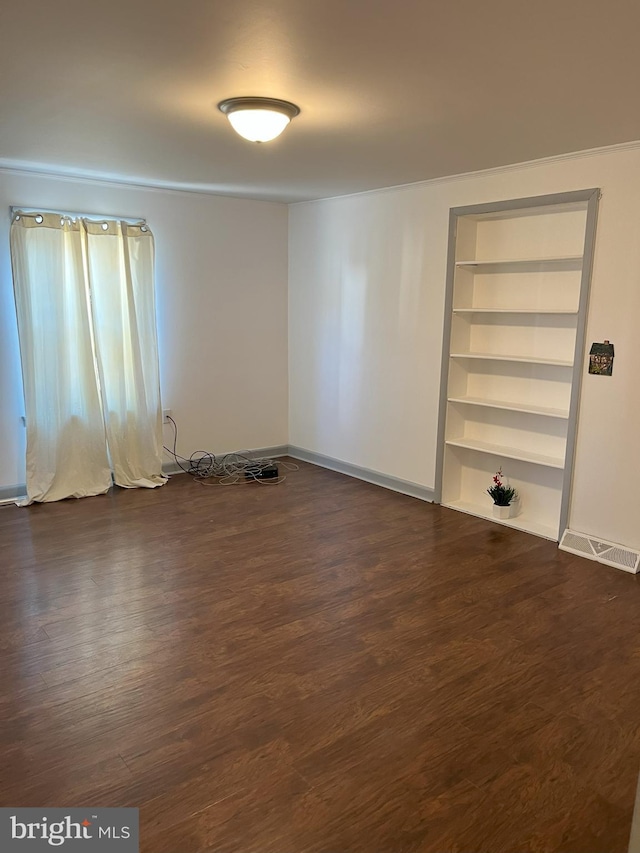 unfurnished room featuring built in features, visible vents, baseboards, and dark wood-style flooring