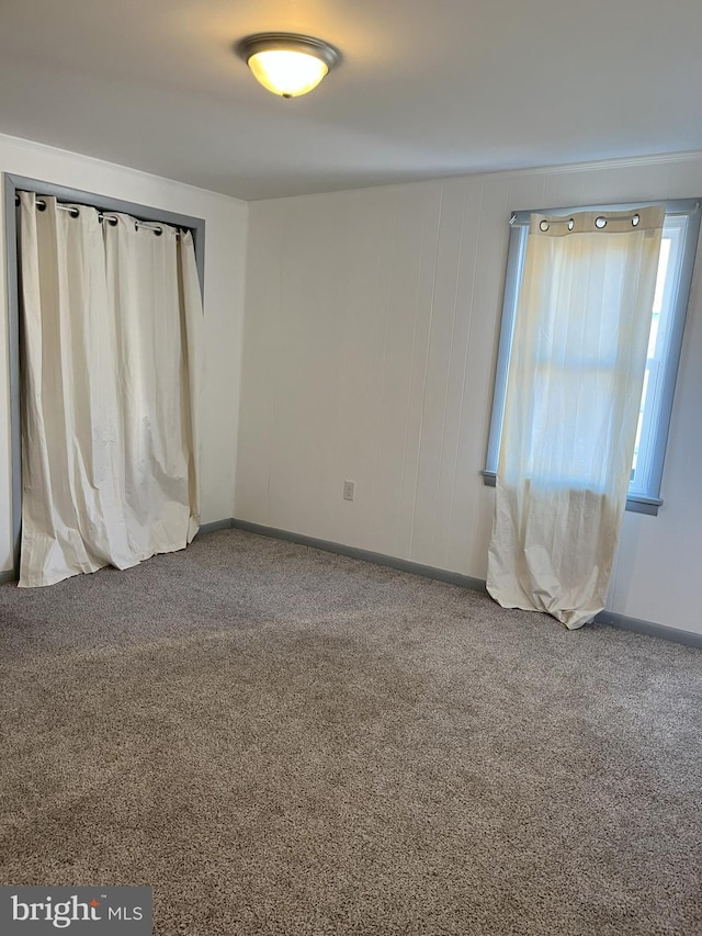 unfurnished room with carpet flooring and baseboards