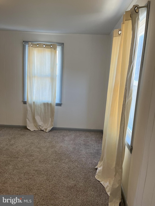 spare room featuring carpet flooring and baseboards