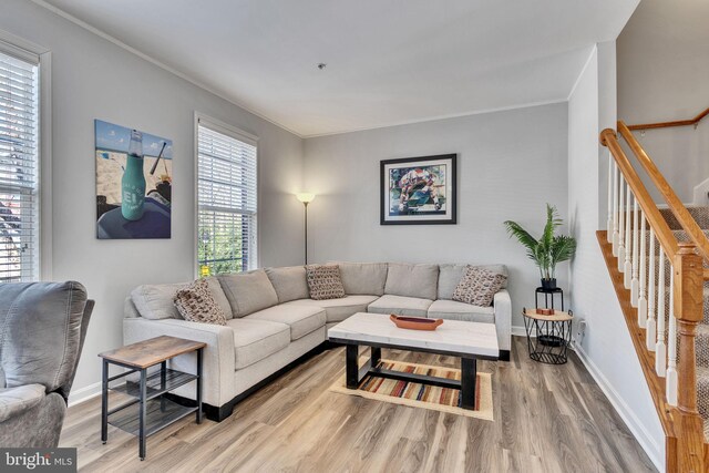 living area with stairs, wood finished floors, and ornamental molding