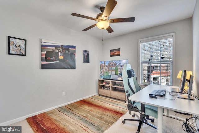 carpeted office space with baseboards and ceiling fan