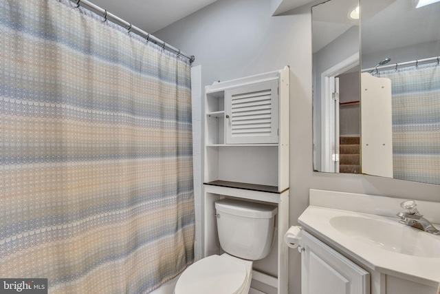 bathroom featuring toilet, vanity, and a shower with curtain