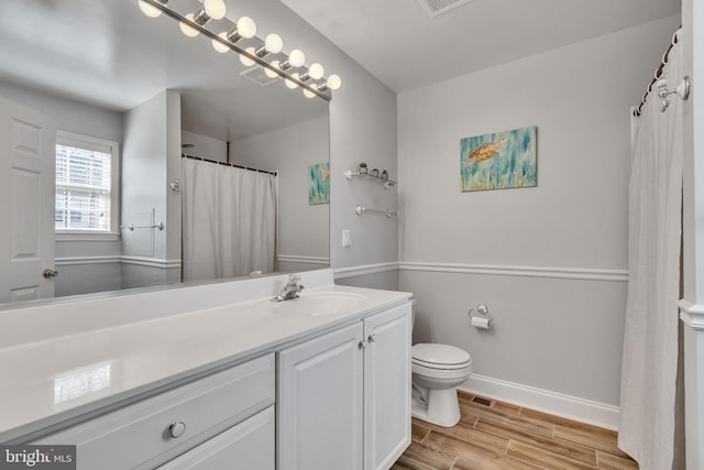 bathroom featuring vanity, visible vents, baseboards, wood tiled floor, and toilet