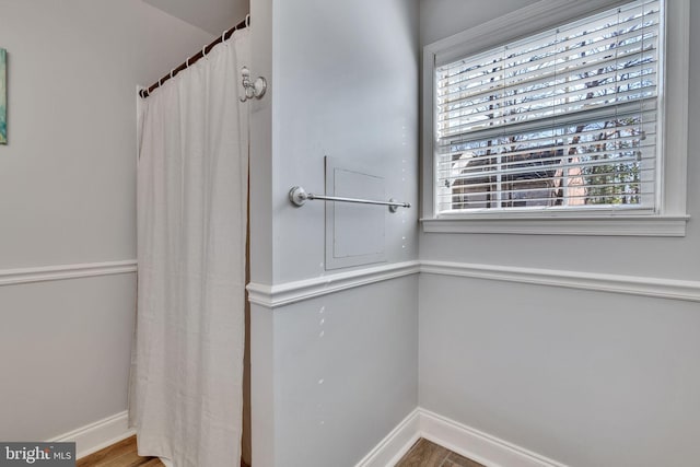 full bath featuring a shower with curtain, wood finished floors, and baseboards