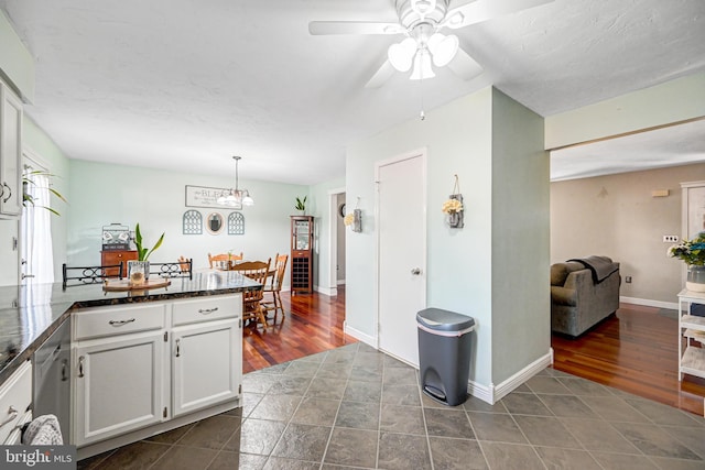 kitchen with wood finished floors, baseboards, pendant lighting, white cabinetry, and ceiling fan with notable chandelier