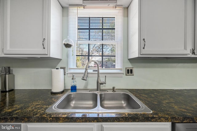 kitchen with a sink, dark countertops, an AC wall unit, and white cabinets