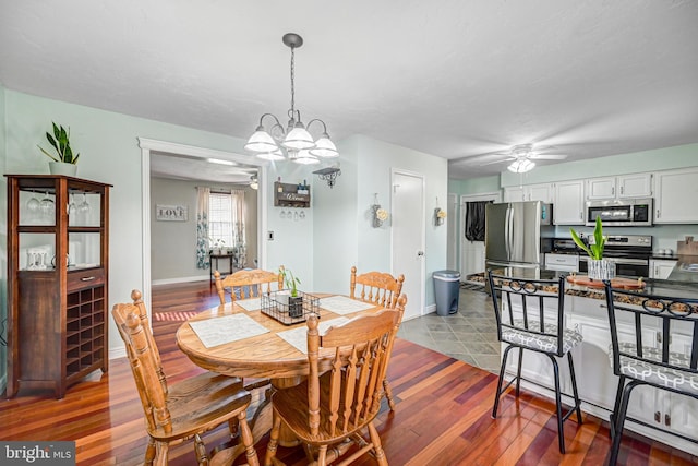 dining area with a baseboard radiator, ceiling fan with notable chandelier, dark wood-style flooring, and baseboards