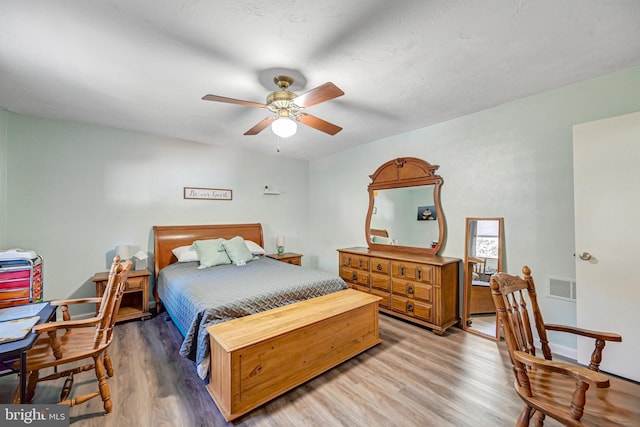 bedroom featuring light wood-style flooring, a ceiling fan, and visible vents