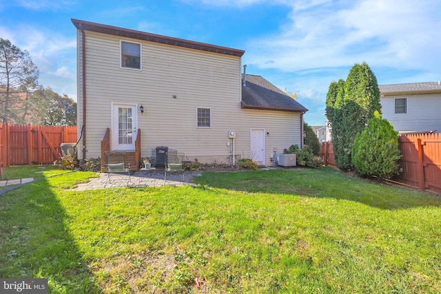 rear view of house with cooling unit, a yard, a fenced backyard, and entry steps