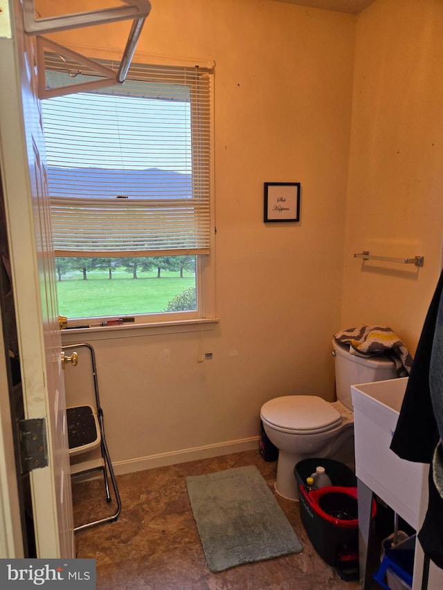 bathroom featuring toilet, a sink, and baseboards