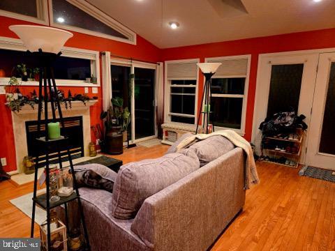 living room featuring a glass covered fireplace, lofted ceiling, and wood finished floors