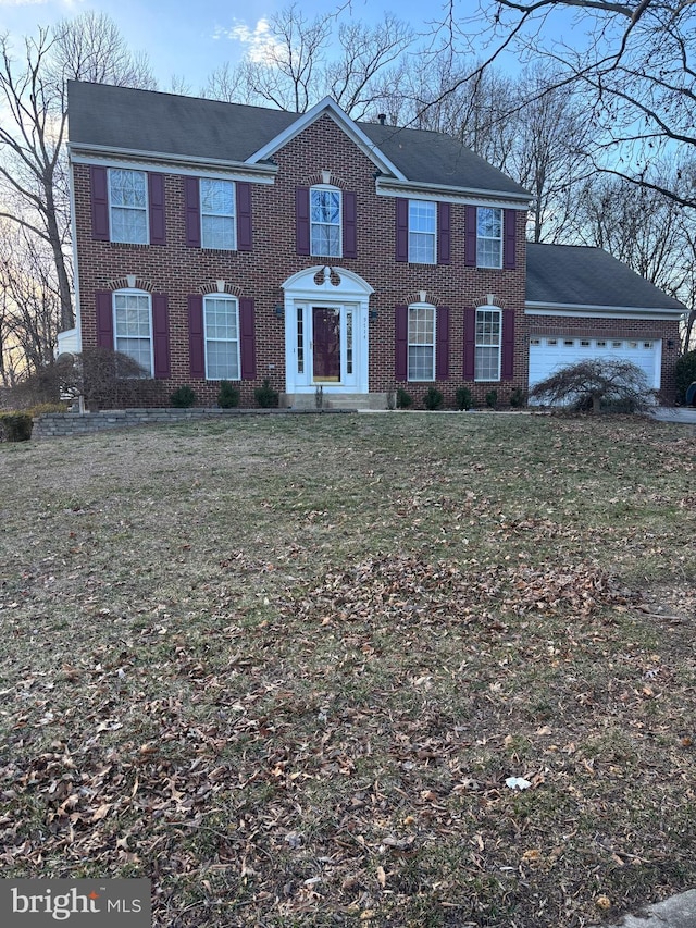 colonial-style house with a front yard, an attached garage, and brick siding