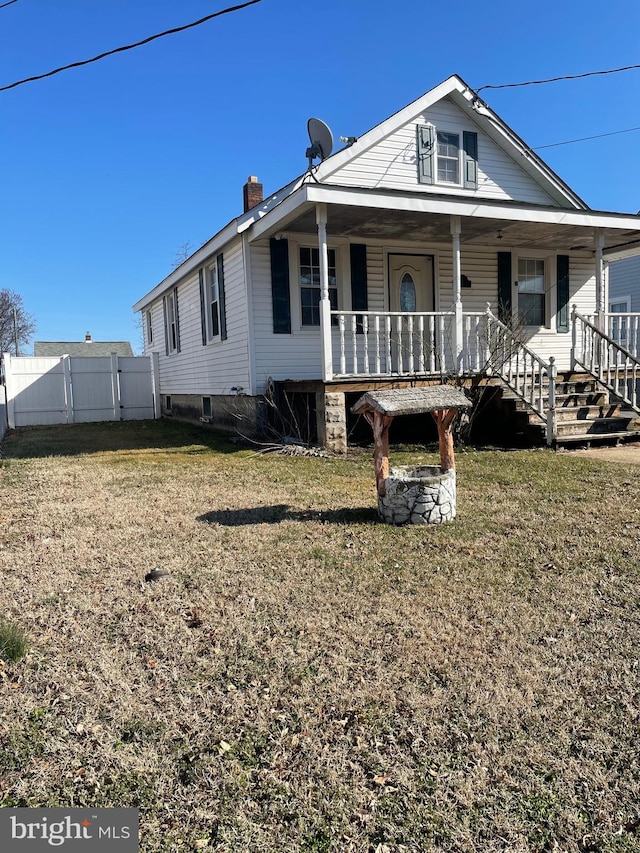 view of front of house with a front yard, a porch, a chimney, and fence